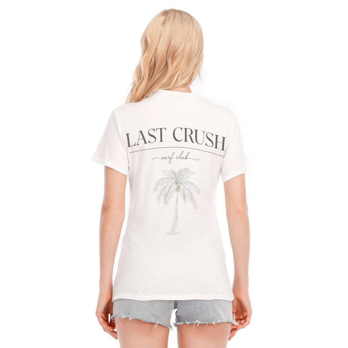 A woman shown from the back wearing a white graphic t-shirt with 'LAST CRUSH surf club' and a palm tree design, paired with gray denim shorts against a white background.